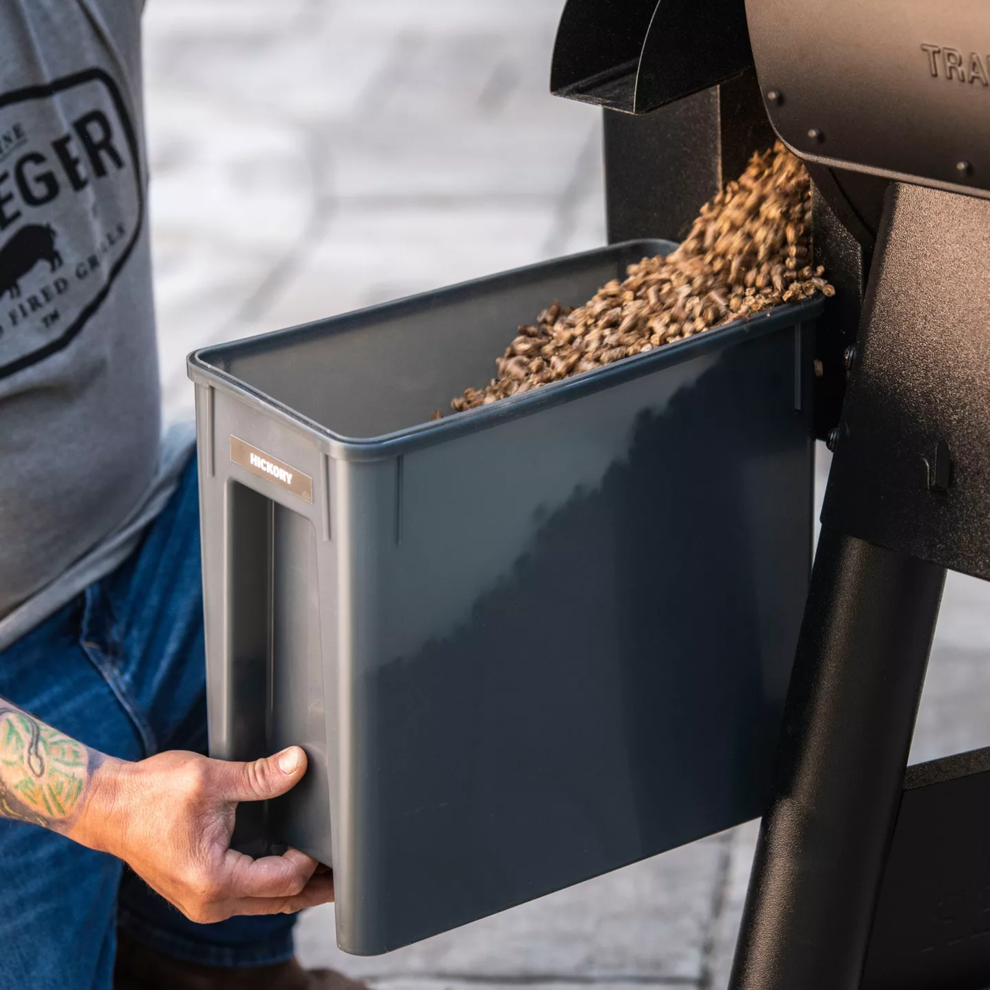 Pellets being emptied out of a smoker grill into a gray bin.