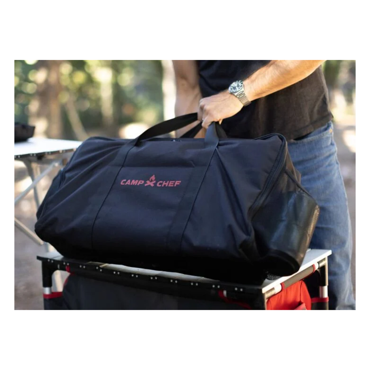Man using a Camp Chef compact cooking system bag outdoors.
