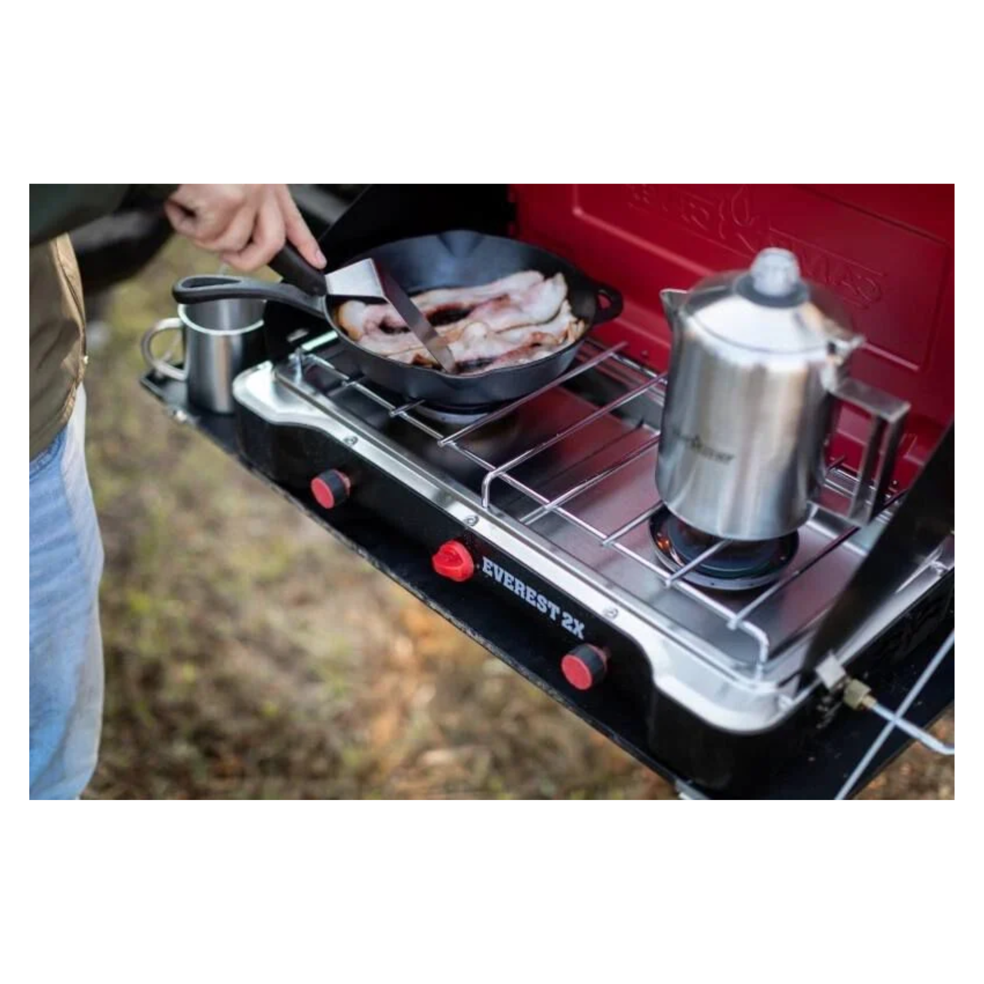 Person cooking food and heating water on open camp chef Everest 