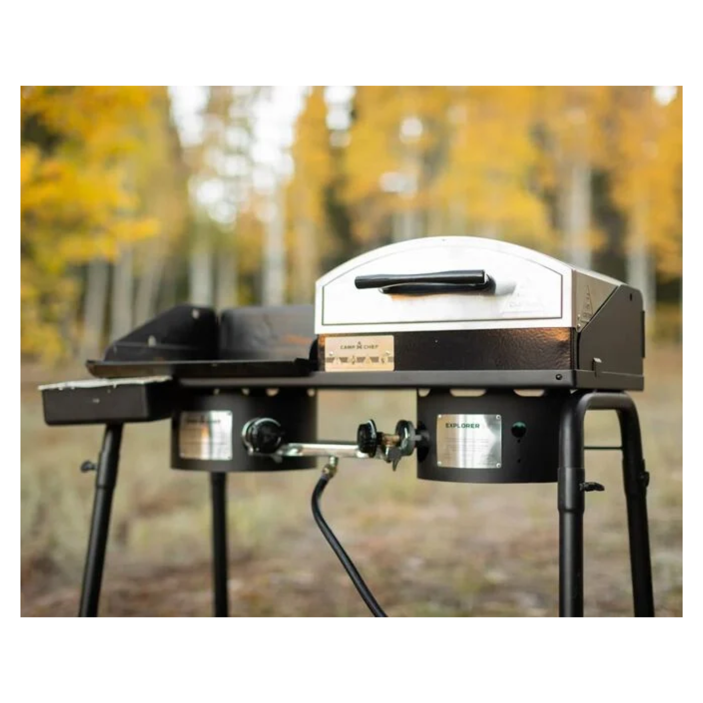 Portable pizza oven on a stand with autumn trees in the background