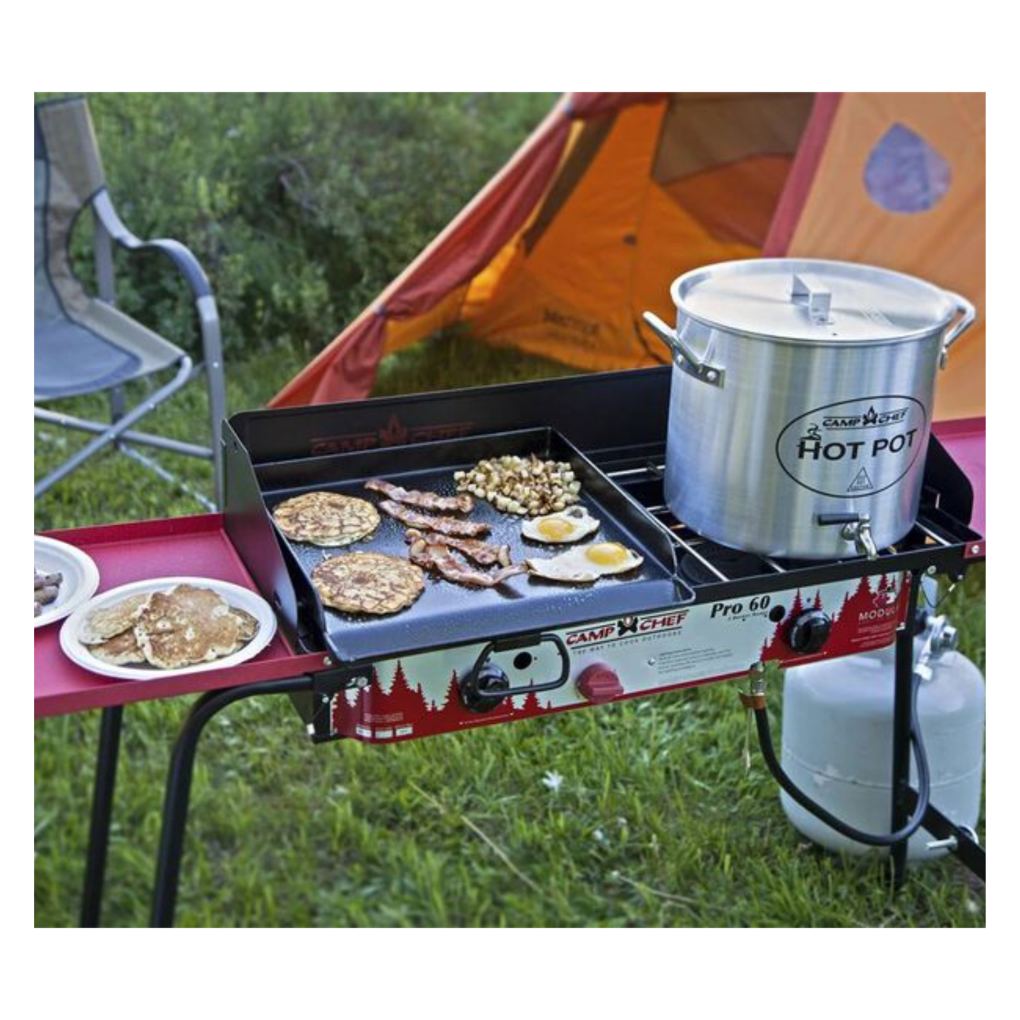 Pancakes, eggs, and bacon cooking on a red and black grill.