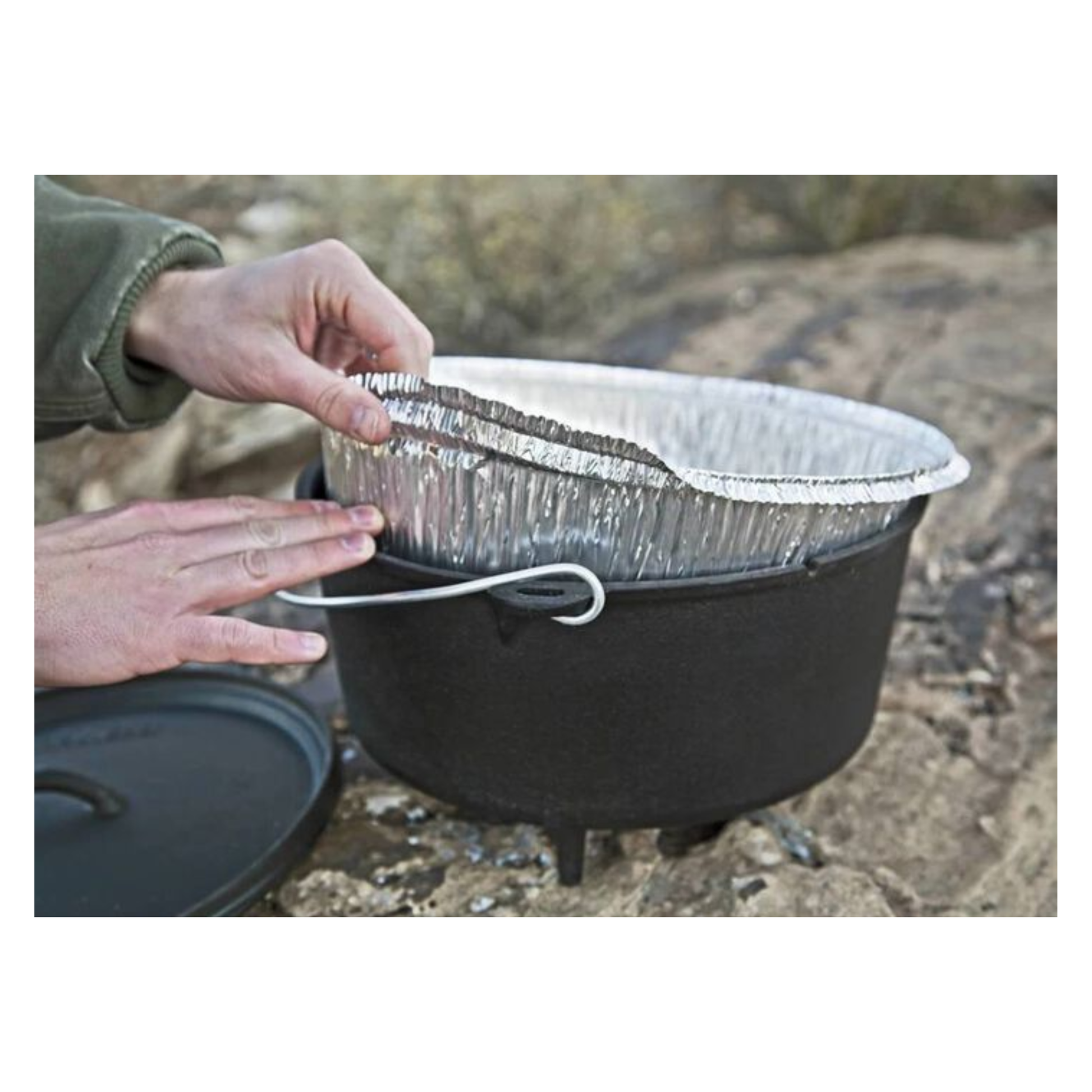 Person placing a disposable liner into a dutch oven outdoors