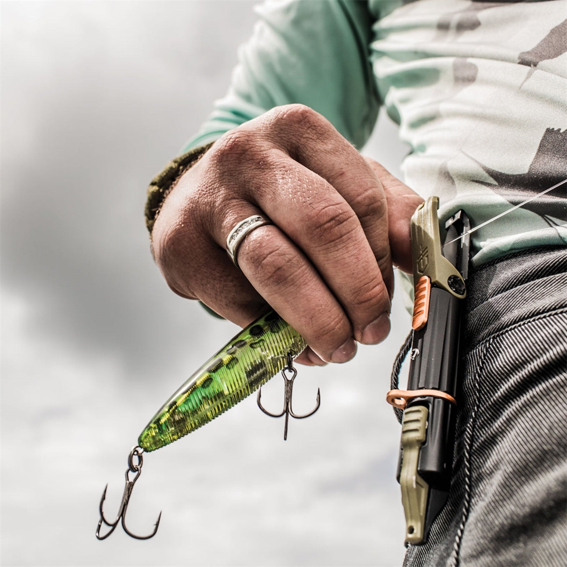 Hand holding a green fishing lure with a blurred background